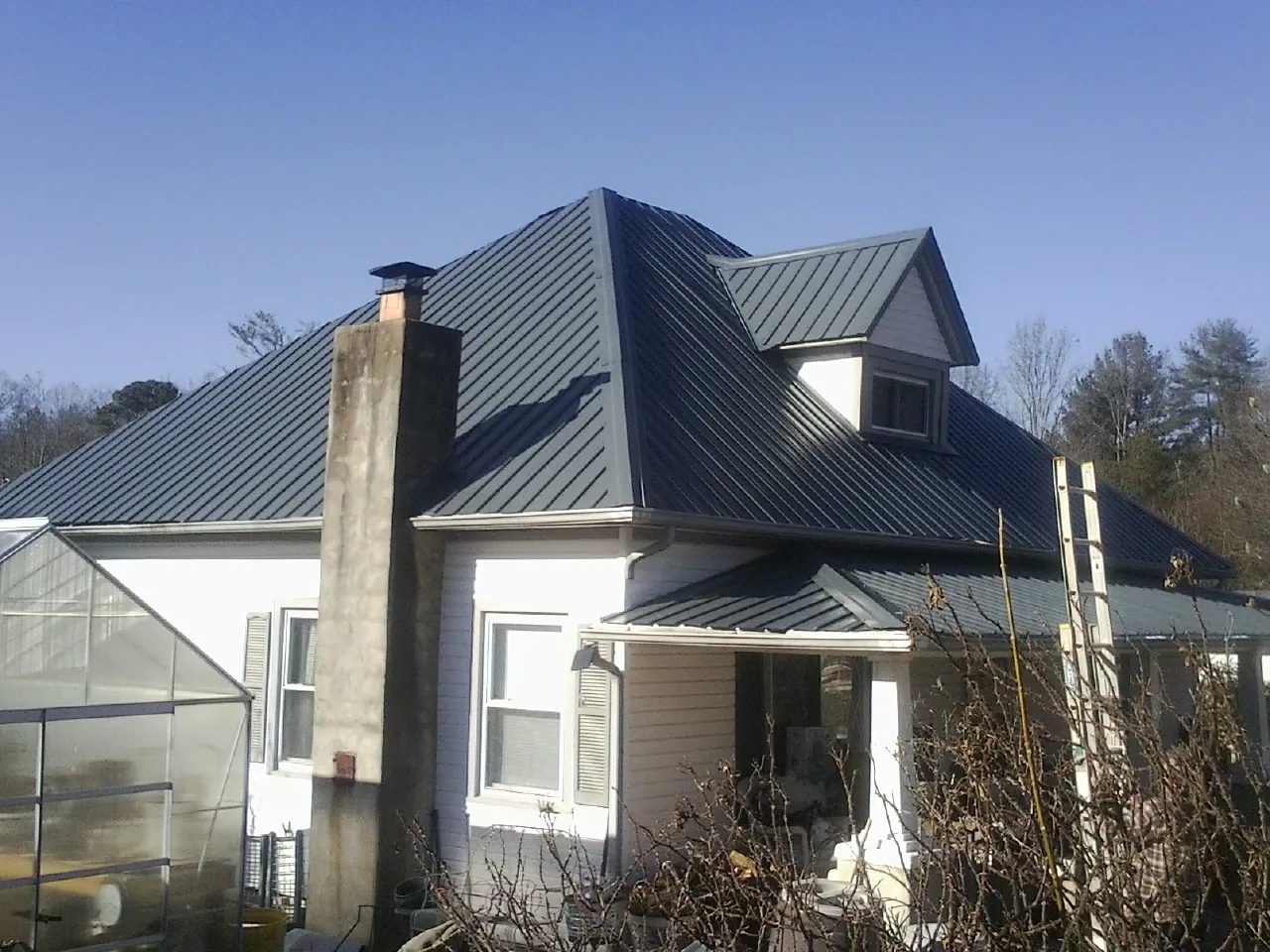 Dark blue standing seam metal roof on a white farmhouse with dormer — Slate & Tile Roof Repair by Roofing Brothers in Seattle