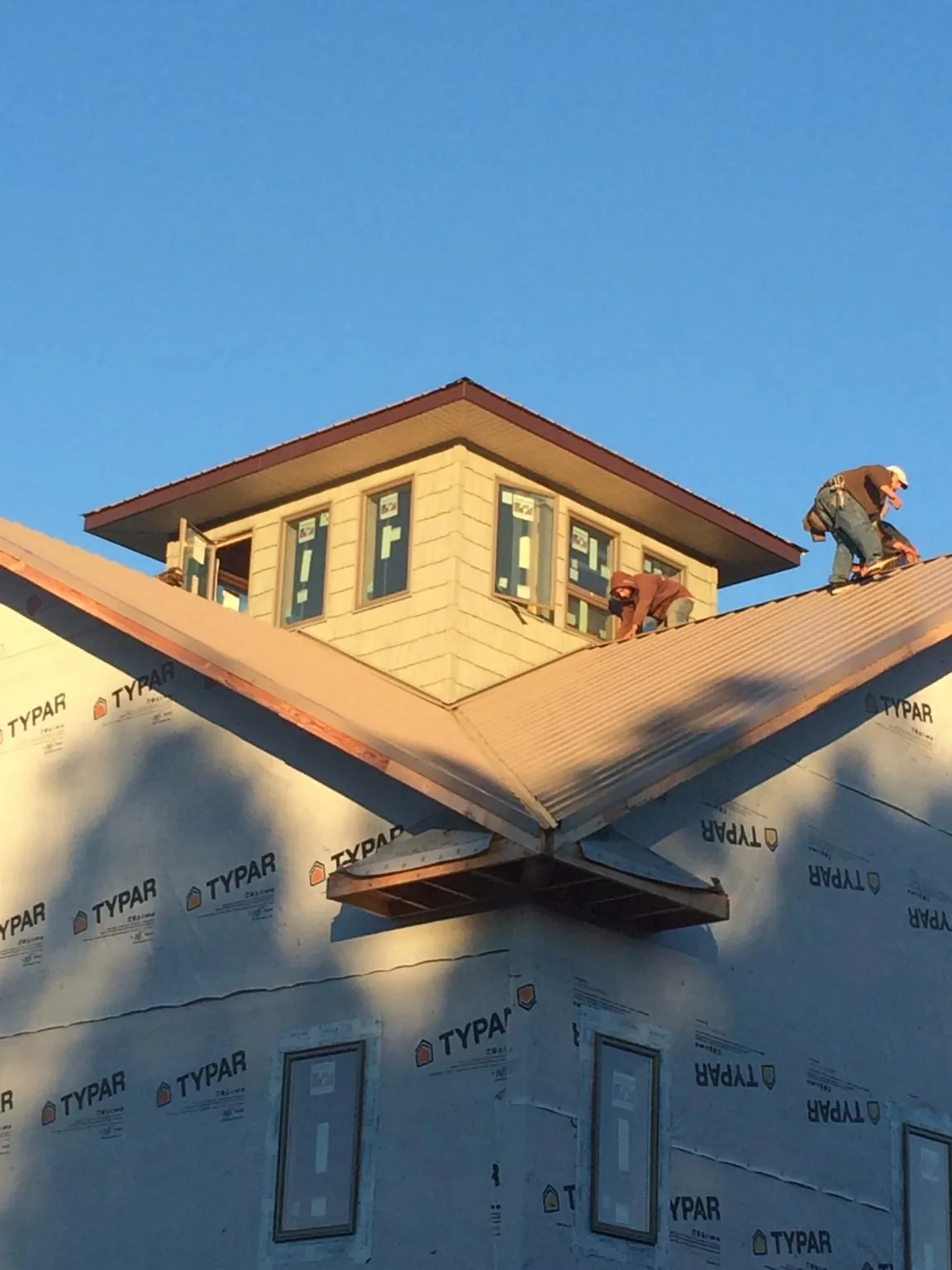 Roofers working around a rooftop cupola on a new metal roof at sunset — Roof Waterproofing in Seattle by Roofing Brothers
